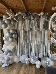 silver and white balloons are hanging from the ceiling