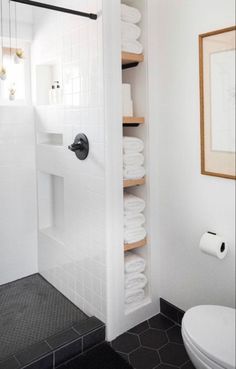 a bathroom with black and white tile flooring and shelves on the wall above the toilet