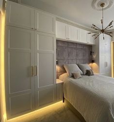 a large white bed sitting in a bedroom under a light