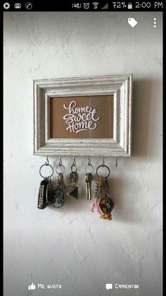 a white frame hanging on the wall with keys and keychains attached to it