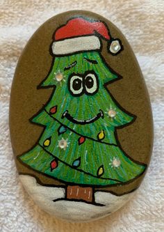 a painted rock with a green christmas tree on it's face and smiling eyes