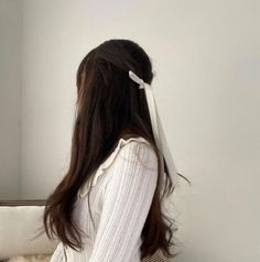 a woman sitting on top of a bed next to a white purse and wearing a white shirt