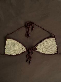 a crocheted bralet is laying on a brown surface with white trimmings