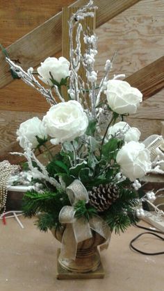 a vase with white flowers and greenery in it