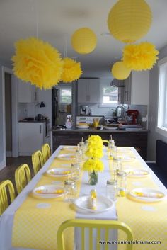 the table is set with yellow and white paper lanterns hanging from the ceiling above it