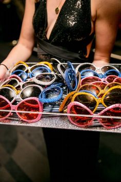 a woman holding a tray full of sunglasses