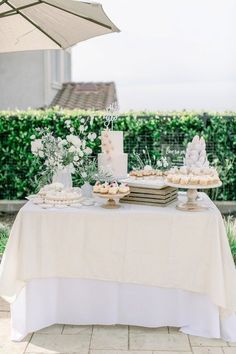 a table topped with cakes and desserts under an umbrella