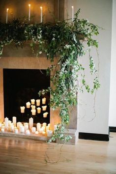 a fireplace with candles and greenery around it