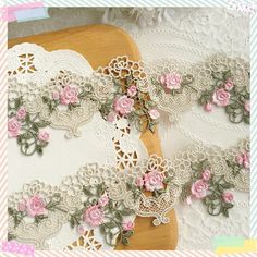 an image of lace with pink flowers on it and a wooden board in the background