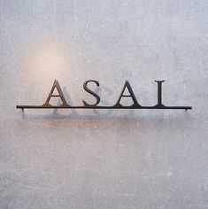 the word asal spelled in metal letters on a white surface with light behind it