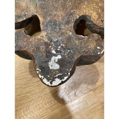 an old metal object with holes in it on a wooden surface, that appears to be rusted