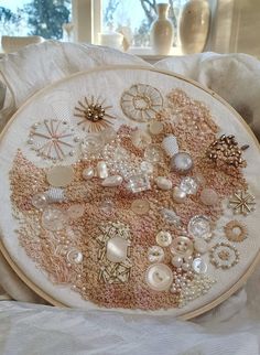 a close up of a embroidery on a pillow with buttons and other things in it