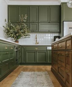 a kitchen with green cabinets and white counter tops, an area rug on the floor