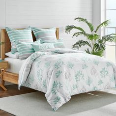 a bed in a bedroom with white walls and green plants on the headboard next to it