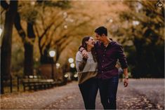 a man and woman are walking down the street holding each other's hands as they laugh