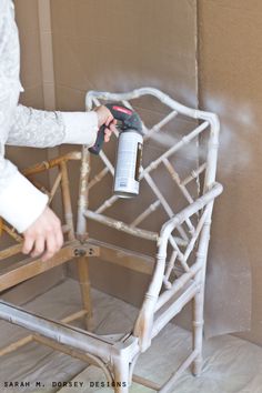 a woman spray painting a chair with white paint on the back and armrests