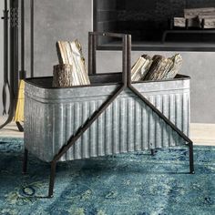 a metal storage container filled with books on top of a blue rug in front of a fireplace