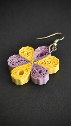 two yellow and purple flower shaped earrings on a black surface