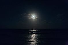 the moon shines brightly over the ocean on a dark night with no one in sight