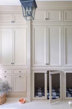 a dog kennel in the middle of a kitchen with white cabinets and drawers on either side