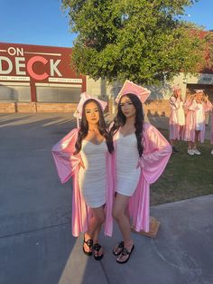 two women in pink graduation gowns posing for a photo at the end of their ceremony