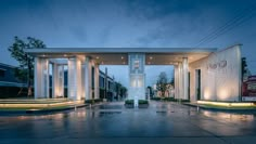 an entrance to a building with columns and lights on the sides at night in front of it