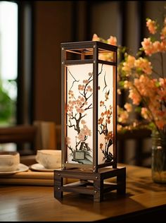 a vase with flowers in it sitting on a table next to a lit up lantern