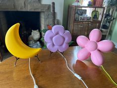 two plastic flowers sitting on top of a table next to a fake moon and flower