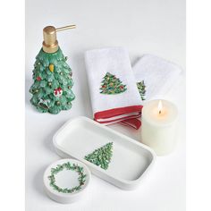 a white table topped with dishes covered in christmas decorations next to a candle and napkins