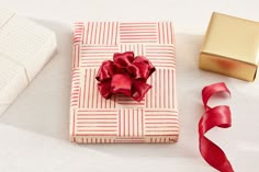 a present wrapped in red ribbon next to a gold gift box