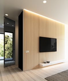 an empty living room with a flat screen tv on the wall and wood flooring