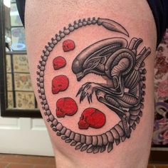 a man with a tattoo on his leg that has red skulls and an alien head in the middle