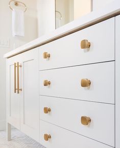 a white dresser with brass handles and knobs