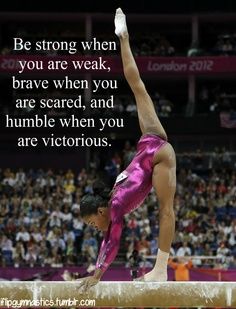 a woman on a balance beam doing a handstand in front of an audience