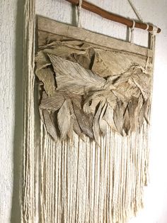 the wall hanging is made out of wood and has fringes on it's sides