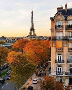 the eiffel tower is seen in the distance from an apartment building with cars parked on the street