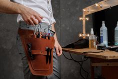 a man is holding his waist bag full of pens and pencils in front of the mirror