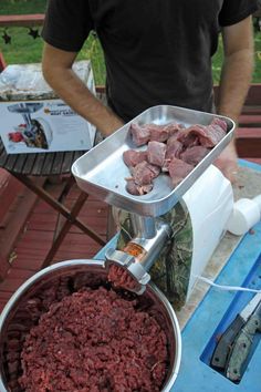 a man standing next to a metal pan filled with meat on top of a table