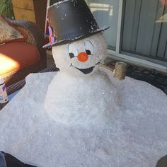 a snowman sitting on top of a pile of snow with a pipe sticking out of it