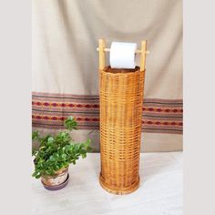 a toilet paper dispenser next to a potted plant on a table