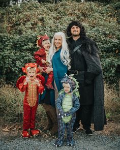 a group of people in costumes standing next to each other on a gravel road with bushes behind them