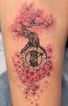 a woman's thigh with pink flowers and a tree tattoo on the side of her leg