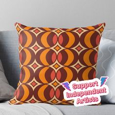 an orange and brown pillow with the words support independent artists on it, sitting on a couch