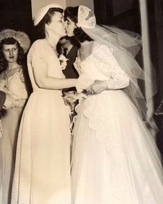 an old photo of two women in wedding dresses and one is kissing the other woman