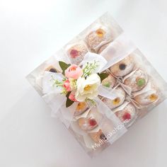 a box filled with pastries and flowers on top of a white tableclothed surface