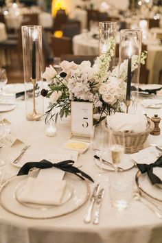 the table is set with white flowers and place settings for guests to sit at it