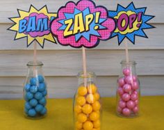 three glass jars filled with candy sitting on top of a yellow tablecloth covered table