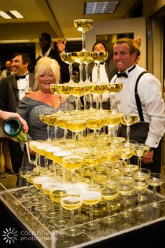 a man and woman are standing in front of a large display of champagne glasses on a table