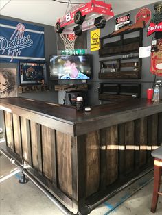 the bar is made out of wood and has several signs hanging on the wall behind it