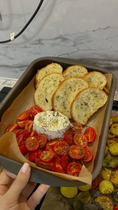 a tray filled with sliced up tomatoes and bread on top of a counter next to other vegetables